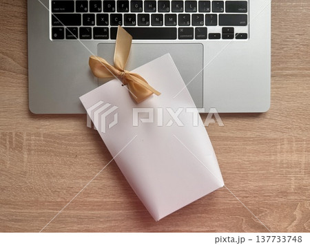 White gift wrap tied with a beige bow on top on a neutral background. High quality photo White gift wrap tied with a beige bow on top on a neutral background. High quality photo 137733748
