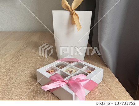 Delicious, sweet handmade chocolates made of white and milk chocolate with whole nuts in a gift box on a light background. High quality photo Delicious, sweet handmade chocolates made of white and milk chocolate with whole nuts in a gift box on a light background. High quality photo 137733752