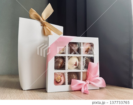 Delicious, sweet handmade chocolates made of white and milk chocolate with whole nuts in a gift box on a light background. High quality photo Delicious, sweet handmade chocolates made of white and milk chocolate with whole nuts in a gift box on a light background. High quality photo 137733765