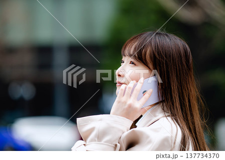 外出先で電話しているビジネスウーマン 外出先で電話しているビジネスウーマン 137734370