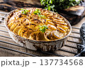 Golden-brown gratin potatoes, neatly arranged in a white ceramic bowl and garnished with fresh herbs. In Slovakia, however, this dish is known primarily at home as French potatoes 137734568