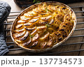 Golden-brown gratin potatoes, neatly arranged in a white ceramic bowl and garnished with fresh herbs. In Slovakia, however, this dish is known primarily at home as French potatoes 137734573