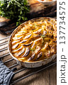 Golden-brown gratin potatoes, neatly arranged in a white ceramic bowl and garnished with fresh herbs. In Slovakia, however, this dish is known primarily at home as French potatoes 137734575