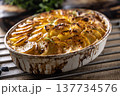 Golden-brown gratin potatoes, neatly arranged in a white ceramic bowl and garnished with fresh herbs. In Slovakia, however, this dish is known primarily at home as French potatoes 137734576