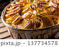 Golden-brown gratin potatoes, neatly arranged in a white ceramic bowl and garnished with fresh herbs. In Slovakia, however, this dish is known primarily at home as French potatoes 137734578
