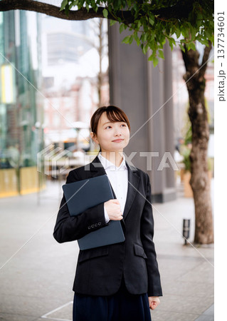 ノートパソコンを胸に抱える若い女性 137734601