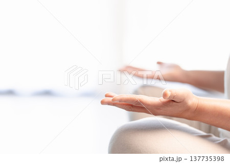 Close-up of hands in yoga meditation mudra during mindfulness practice, soft bright background with copy space. Calm wellness concept for relaxation, breathing, zen and mental health. Close-up of hands in yoga meditation mudra during mindfulness practice, soft bright background with copy space. Calm wellness concept for relaxation, breathing, zen and mental health. 137735398