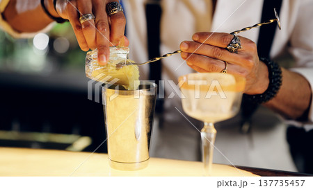 Bartender pouring ingredients into a cocktail shaker Bartender pouring ingredients into a cocktail shaker 137735457