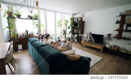 Gay couple relaxing on couch at home, using smartphones Gay couple relaxing on couch at home, using smartphones 137735503