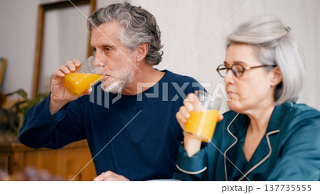 Senior couple drinking orange juice at morning breakfast Senior couple drinking orange juice at morning breakfast 137735555