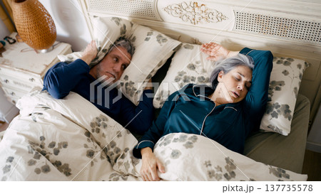 Senior man disturbed by partner snoring in bed Senior man disturbed by partner snoring in bed 137735578