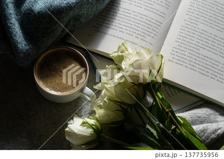 A cup of coffee, an book, a bouquet of white roses and a warm sweater A cup of coffee, an book, a bouquet of white roses and a warm sweater 137735956