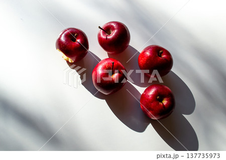 Five red ripe apples lying on a white table and their shadows Five red ripe apples lying on a white table and their shadows 137735973
