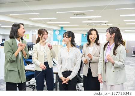 明るいオフィスで談笑しコミュニケーションをとる女子社員のグループ 137736348