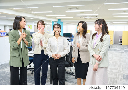 明るいオフィスで談笑しコミュニケーションをとる女子社員のグループ 137736349