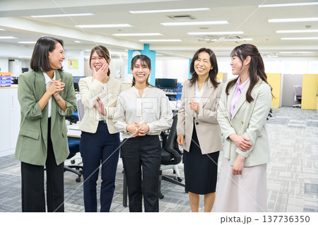 明るいオフィスで談笑しコミュニケーションをとる女子社員のグループ 137736350