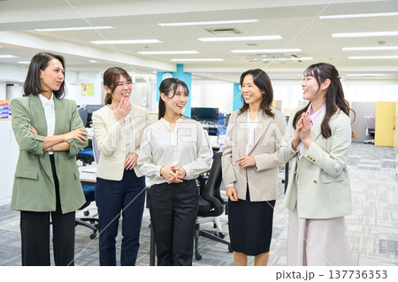 明るいオフィスで談笑しコミュニケーションをとる女子社員のグループ 137736353
