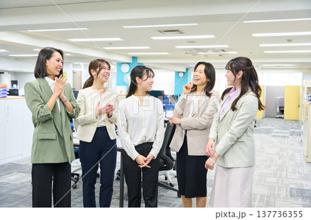 明るいオフィスで談笑しコミュニケーションをとる女子社員のグループ 明るいオフィスで談笑しコミュニケーションをとる女子社員のグループ 137736355