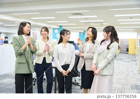 明るいオフィスで談笑しコミュニケーションをとる女子社員のグループ 137736356