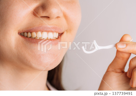 Smiling woman holding floss pick, dental hygiene and healthy teeth concept 137739491