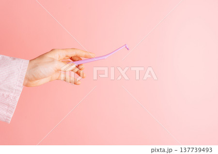 Hand holding a single tuft toothbrush on pink background, clean dental hygiene tool minimal flat lay Hand holding a single tuft toothbrush on pink background, clean dental hygiene tool minimal flat lay 137739493