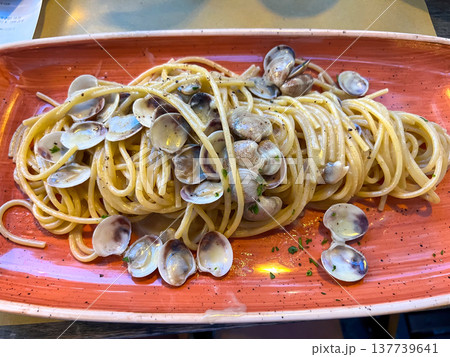 View of a full plate of Italian pasta vongole on a trattoria table in Italy View of a full plate of Italian pasta vongole on a trattoria table in Italy 137739641