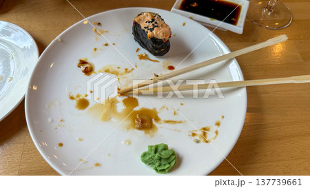 Single Sushi Roll on Nearly Empty Plate with Chopsticks and Soy Sauce Splash Single Sushi Roll on Nearly Empty Plate with Chopsticks and Soy Sauce Splash 137739661