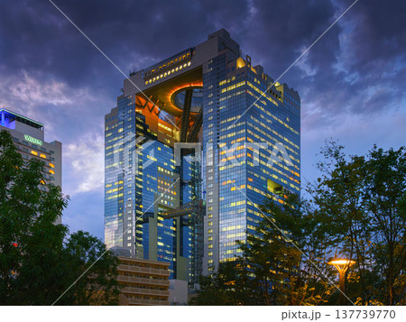 Osaka, Japan - Sep 25 2024, Panoramic view through trees on Umeda Sky Building with an illuminating ring at the top between two towers, at evening, without people, Osaka, Japan 137739770
