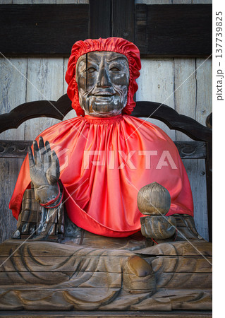 Nara, Japan - Sep 26 2024, close up view of Statue of Pindola Bharadvaja in front of Great Buddha Hall of Todaiji temple, sitting on a chair in red clothes, without people, Nara, Japan Nara, Japan - Sep 26 2024, close up view of Statue of Pindola Bharadvaja in front of Great Buddha Hall of Todaiji temple, sitting on a chair in red clothes, without people, Nara, Japan 137739825