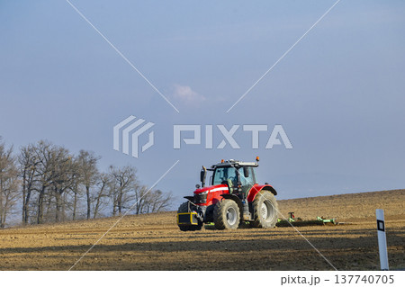 Red tractor plowing field in Hlina, Jihomoravsky kraj Red tractor plowing field in Hlina, Jihomoravsky kraj 137740705