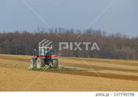 Red agricultural tractor tilling soil in Hlina field 137740706