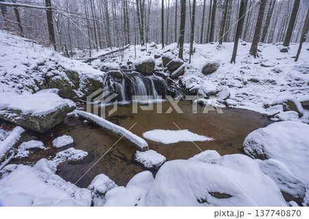 Waterfall cascading through snowy forest in Liberecky kraj Waterfall cascading through snowy forest in Liberecky kraj 137740870
