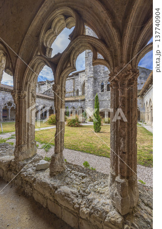 Ornate stone arches framing cloister garden in La Romieu 137740904
