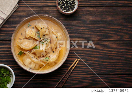 Gyoza dumplings broth soup chopsticks wooden background bowl asian wontons Gyoza dumplings broth soup chopsticks wooden background bowl asian wontons 137740972