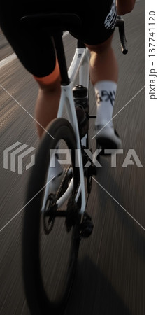 Cyclist propelling modern road bike forward on asphalt road. Cyclist riding bicycle with motion blur, emphasizing speed, fitness, and movement Cyclist propelling modern road bike forward on asphalt road. Cyclist riding bicycle with motion blur, emphasizing speed, fitness, and movement 137741120