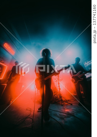 Live band performing during an energetic music concert. Musicians playing rock music on stage with dramatic red and blue lighting Live band performing during an energetic music concert. Musicians playing rock music on stage with dramatic red and blue lighting 137741160