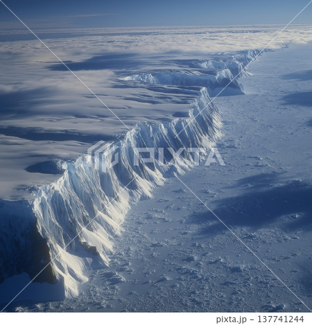 Antarctic frozen landscape showing vast ice and towering mountains. Frozen Antarctic landscape with towering, snow-covered mountains, glaciers, and sea ice 137741244