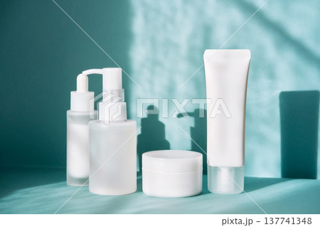 White cosmetic bottles displaying skincare products on blue background White cosmetic bottles displaying skincare products on blue background 137741348