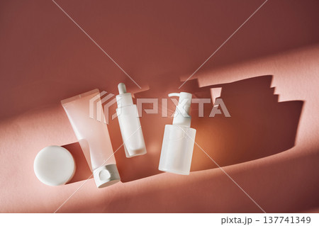 Skincare product bottles with dropper and pump on pink background Skincare product bottles with dropper and pump on pink background 137741349