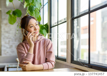 窓際で電話する女性 137741457