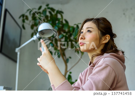 女性がスマホを操作し上を見上げる 137741458