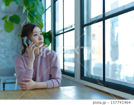窓際で電話する女性 137741464