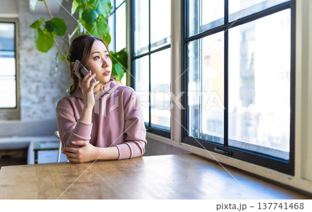 窓際で電話する女性の表情 137741468