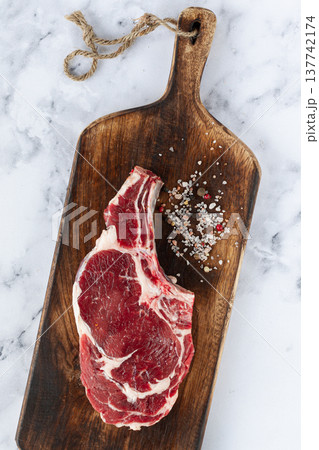 raw rib eye steak, cowboy steak, wooden chopping board, marble table, top view, no people, raw rib eye steak, cowboy steak, wooden chopping board, marble table, top view, no people, 137742174
