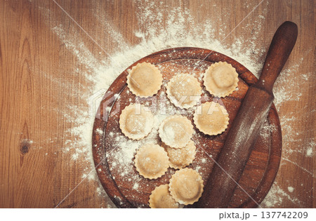 fresh raw, uncooked ravioli, on a cutting board, with a rolling pin for dough, wooden background, no people, fresh raw, uncooked ravioli, on a cutting board, with a rolling pin for dough, wooden background, no people, 137742209