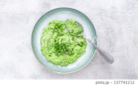 Delicious green pea puree served in a stylish bowl garnished with fresh peas and microgreens for a healthy meal Delicious green pea puree served in a stylish bowl garnished with fresh peas and microgreens for a healthy meal 137742212