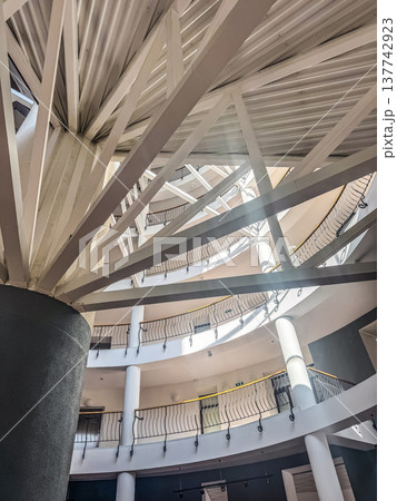 Architectural detail of a modern multi-story atrium with a complex geometric roof structure. Architectural detail of a modern multi-story atrium with a complex geometric roof structure. 137742923