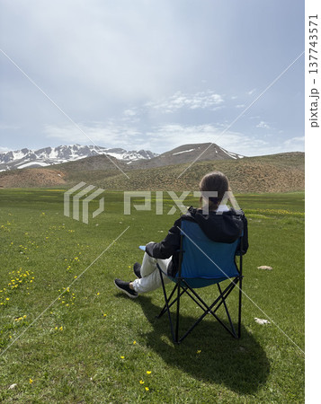 Relaxing mountain scenery. Mountains person chair.mountains in spring silhouette of a tourist Relaxing mountain scenery. Mountains person chair.mountains in spring silhouette of a tourist 137743571