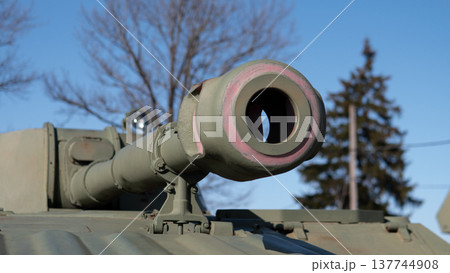 Closeup Tank Barrel With Tree Silhouette, Precisionmachined Steel Tube And Bore Visible With Painted Camouflage Ring Shallow Depth Of Field Isolates Rugged Muzzle, Hinting At Readiness Closeup Tank Barrel With Tree Silhouette, Precisionmachined Steel Tube And Bore Visible With Painted Camouflage Ring Shallow Depth Of Field Isolates Rugged Muzzle, Hinting At Readiness 137744908