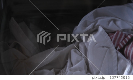 Crumpled White Sheets And Striped Fabric, Dimly Lit Tumble Of Linens Spilling Into Shadowed Corner, Soft Folds And Muted Tones, Intimate Domestic Mood With Textured Creases And Layered Heap Crumpled White Sheets And Striped Fabric, Dimly Lit Tumble Of Linens Spilling Into Shadowed Corner, Soft Folds And Muted Tones, Intimate Domestic Mood With Textured Creases And Layered Heap 137745016